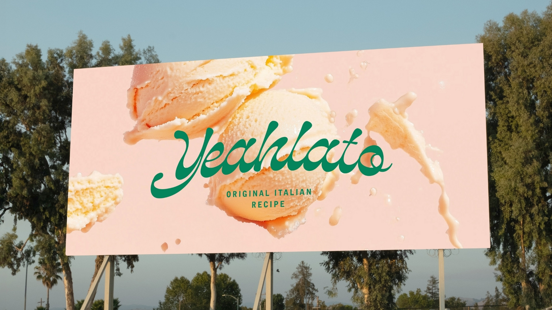  En stor reklampelare utomhus som visar Yeahlatos lekfulla logotyp i grönt mot en rosa bakgrund med aptitretande glasskulor och stänk av mjölk, under texten ”Original Italian Recipe”.