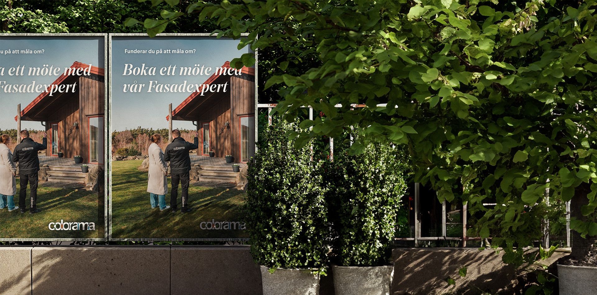  Utomhusreklam för Colorama med rubriken ”Boka ett möte med vår Fasadexpert” placerad invid grönskande buskar.