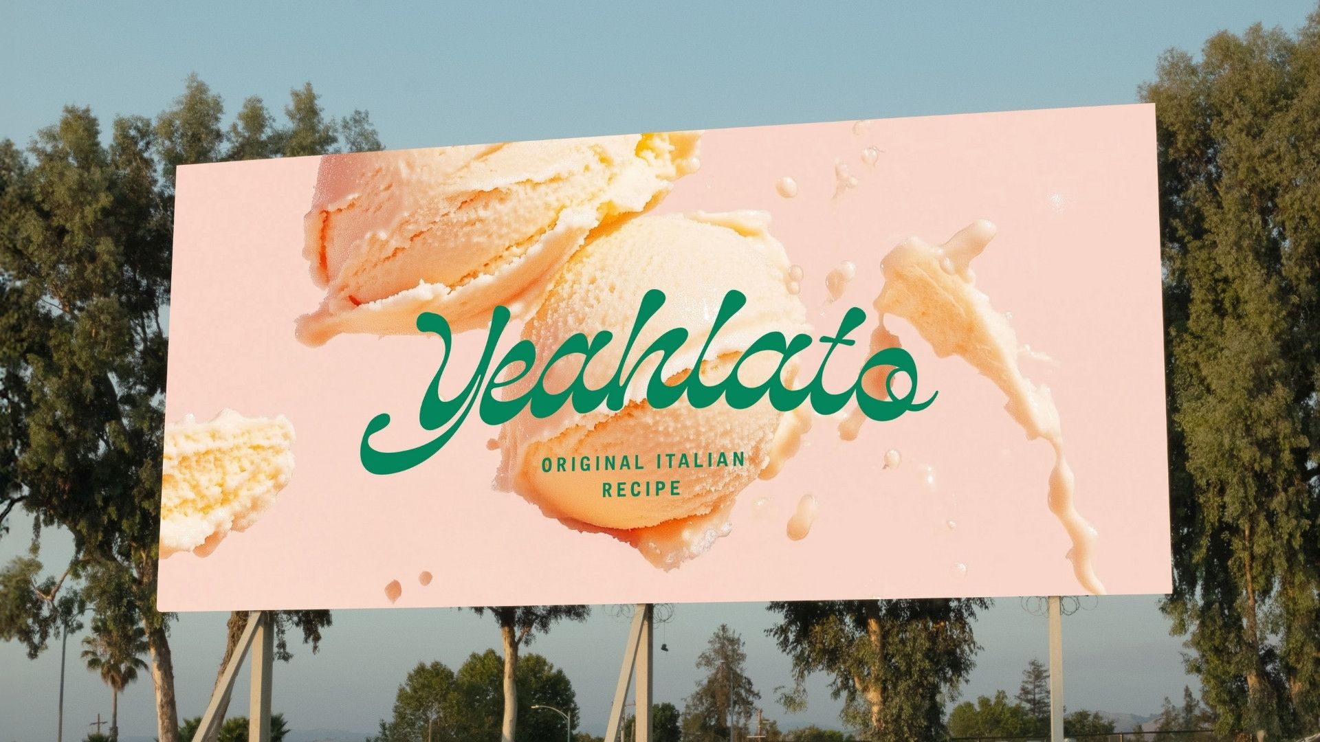  En stor reklampelare utomhus som visar Yeahlatos lekfulla logotyp i grönt mot en rosa bakgrund med aptitretande glasskulor och stänk av mjölk, under texten ”Original Italian Recipe”.