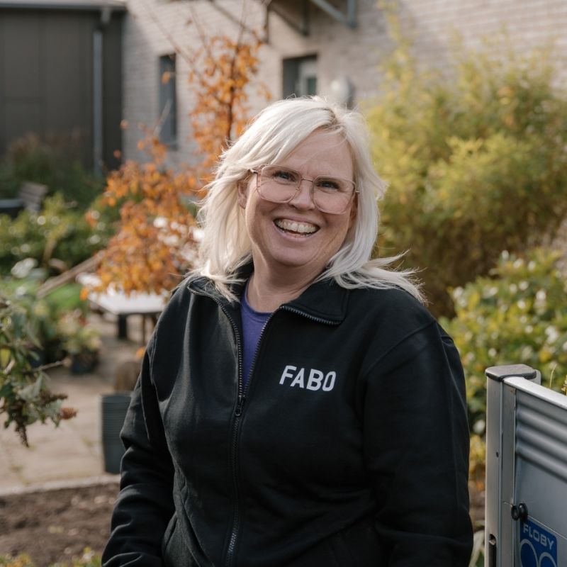 En leende medarbetare från Fabo i profilkläder utomhus, vilket fångar den personliga och engagerade service som kännetecknar verksamheten