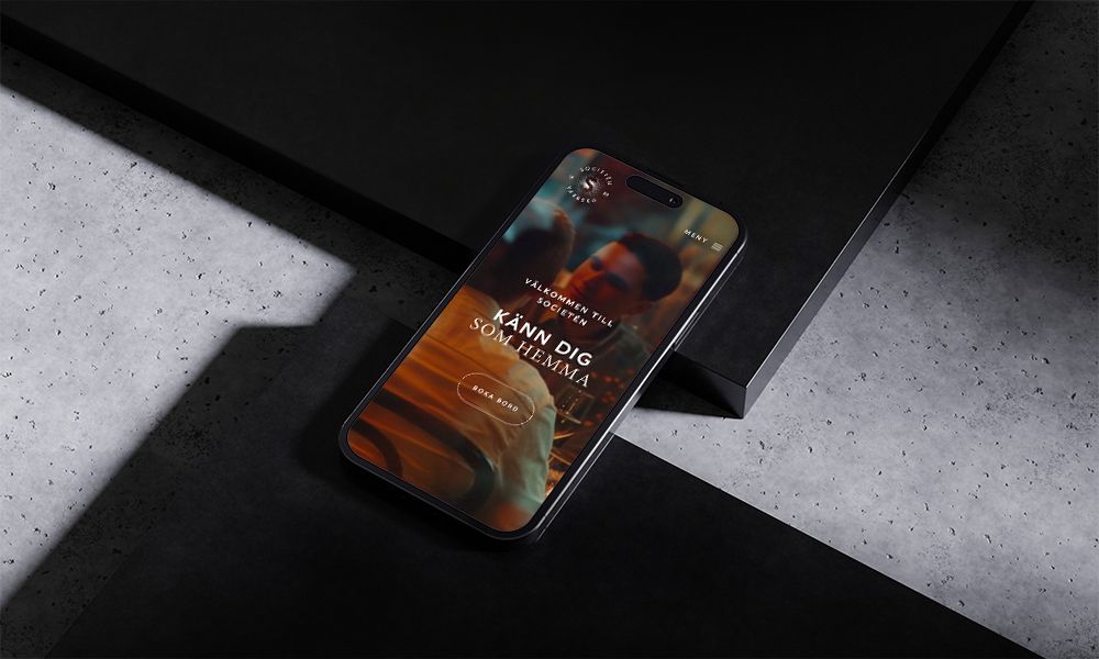 Societéns hemsida i mobilversion med en välkomnande bild från restaurangmiljön och knappen ”Boka bord”.