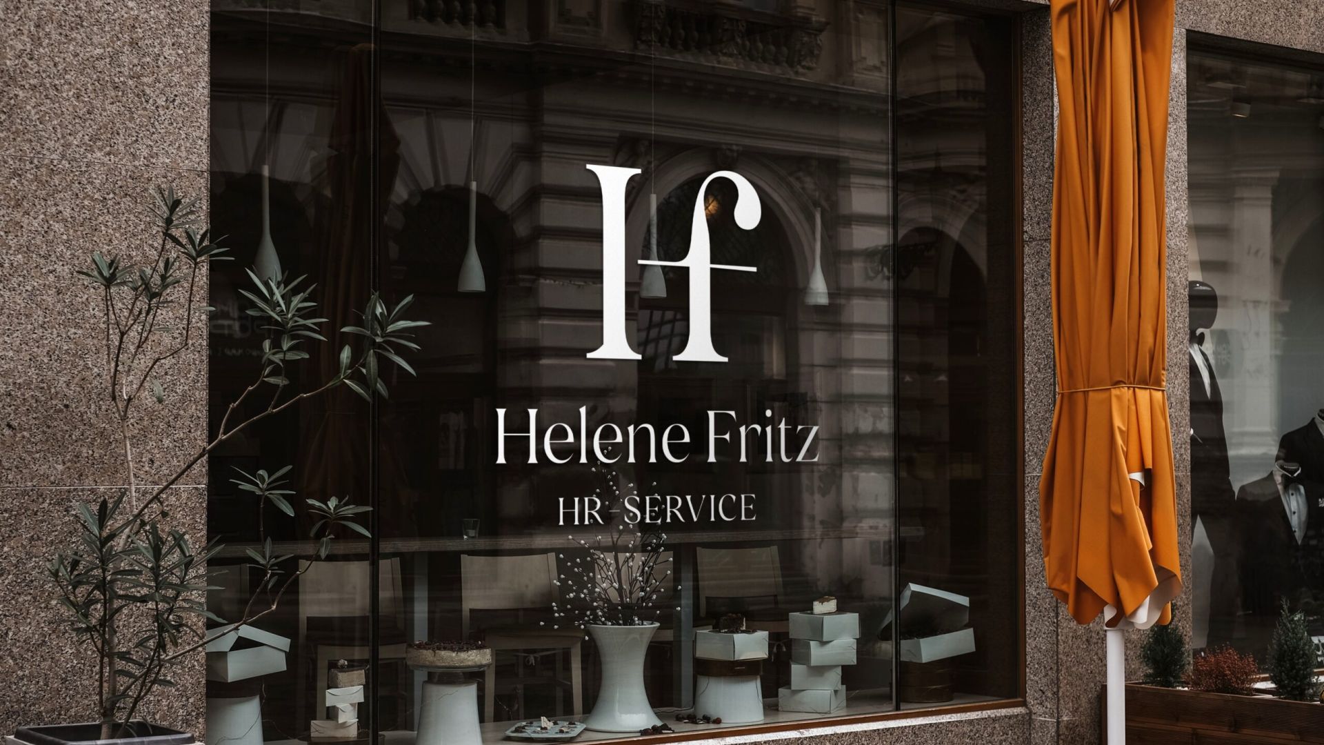 En stilren logotyp för Helene Fritz HR-Service monterad i vitt på ett fönster till en lokal. Designen kombinerar elegant typografi med ett modernt och personligt uttryck.