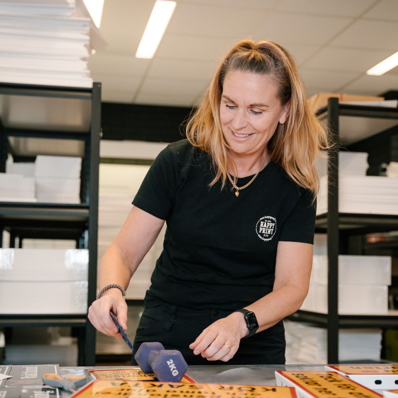 Kvinna som arbetar med skyltproduktion hos Happy Print i en verkstadsmiljö.