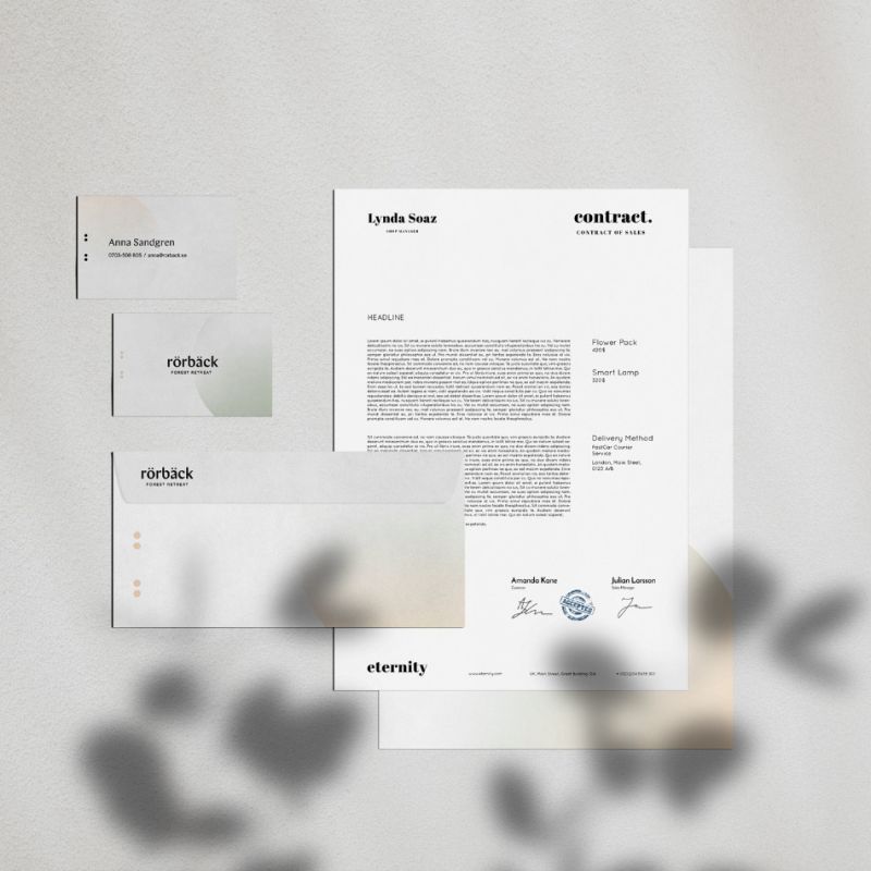  En samling brevpapper och kontorsmaterial för Rörbäck Forest Retreat, inklusive visitkort, kuvert och ett avtalsdokument med minimalistisk design.