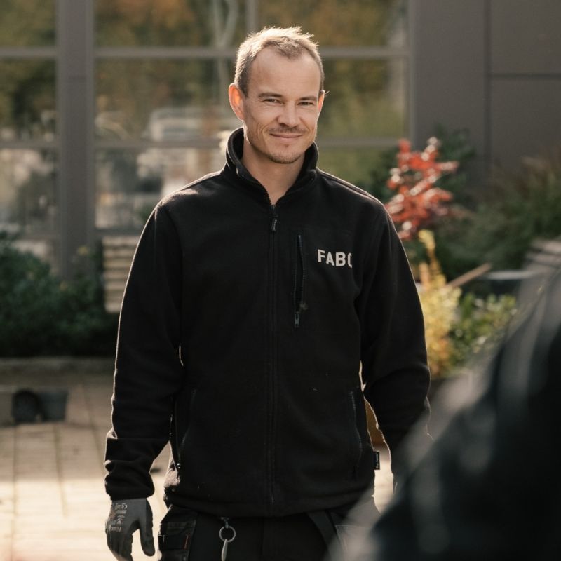 En medarbetare från Fabo i svart profiljacka ler mot kameran, vilket förmedlar ett mänskligt och tillgängligt bemötande i organisationen.