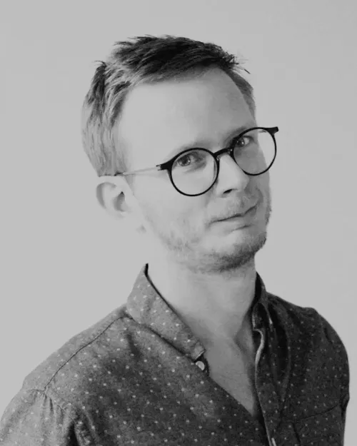 Porträtt av Joel Lindberg, Art Director, med glasögon och kort hår, iklädd en mönstrad skjorta.