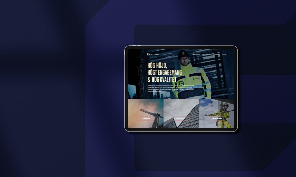 En surfplatta som visar Gottskärs nya webbsida mot en mörkblå bakgrund. Skärmen visar huvudrubriken ”Hög höjd, högt engagemang & hög kvalitet” tillsammans med bilder på personal och pågående byggprojekt.