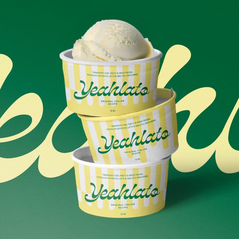Tre staplade glassbägare från Yeahlato med ett gult och vitt ränder-mönster och grön logotyp. Den översta bägaren är fylld med en krämig kula vaniljgelato mot en kontrasterande mörkgrön bakgrund.