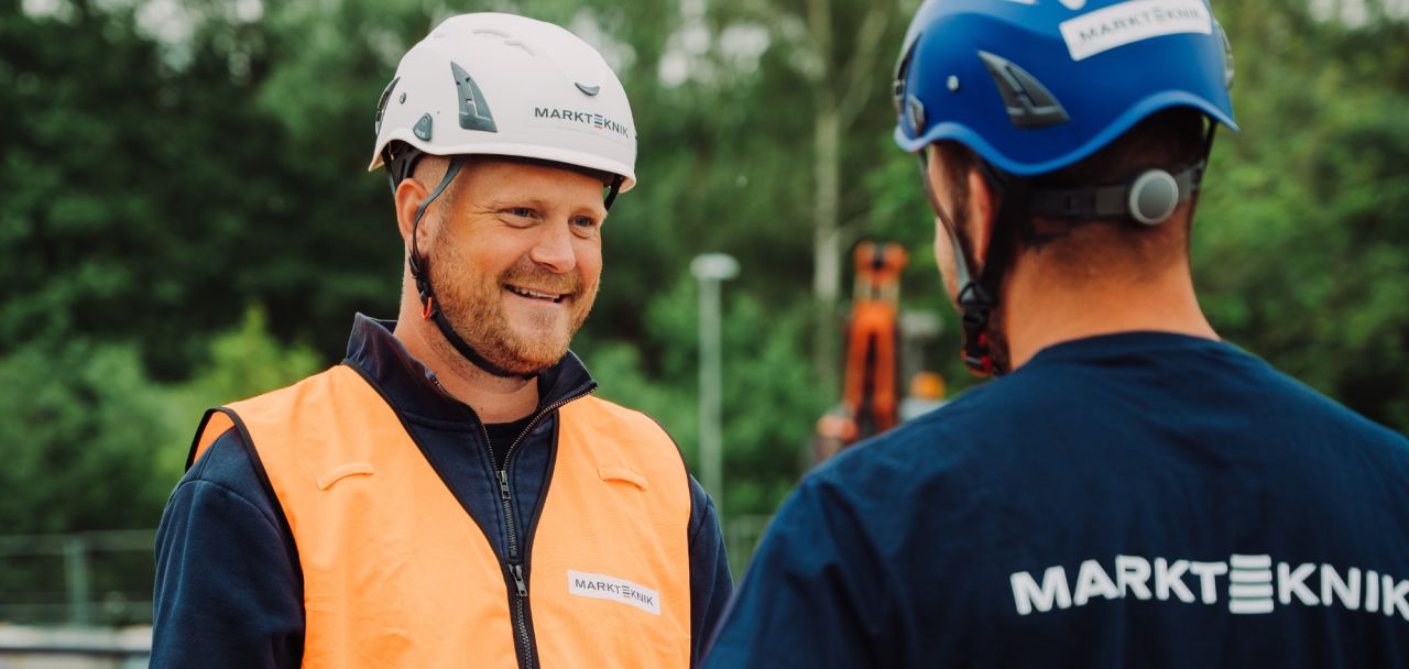 Två medarbetare från Markteknik i glatt samtal på arbetsplatsen.