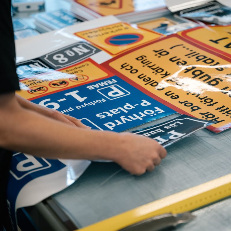 Olika typer av varningsskyltar och parkeringsskyltar under produktion hos Happy Print.