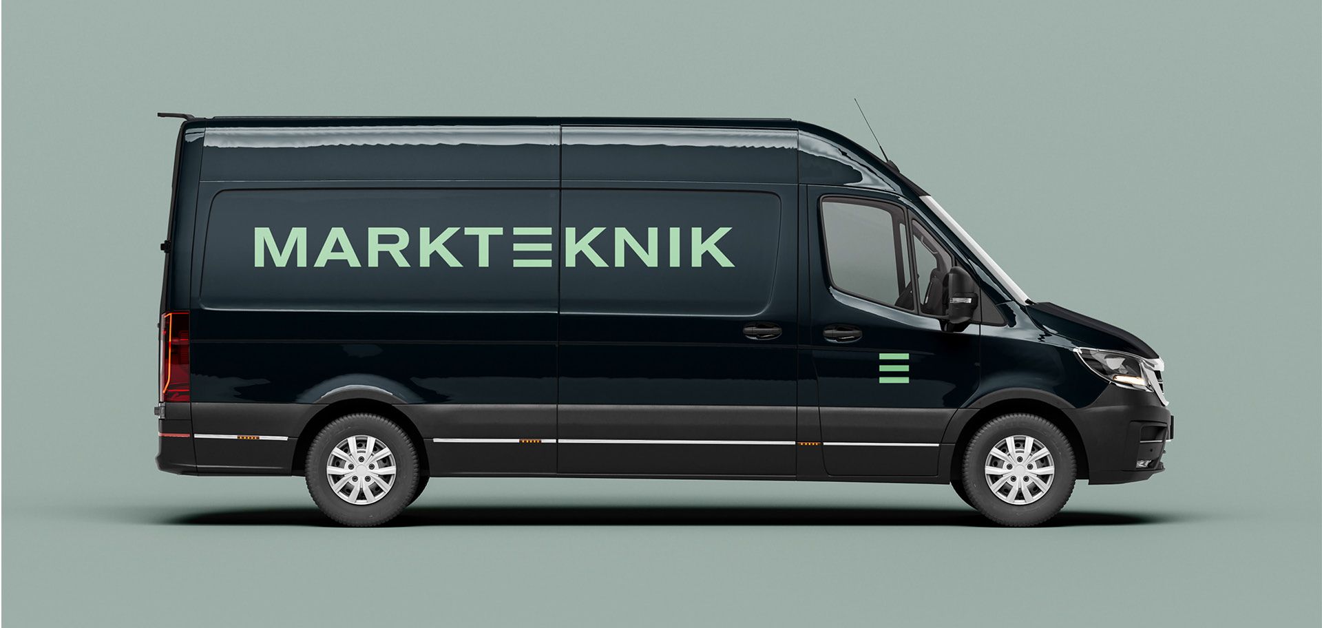 En mörkblå transportbil med Marktekniks nya logotyp i ljusgrönt på sidan, vilket visar hur den grafiska profilen appliceras på företagets fordon.