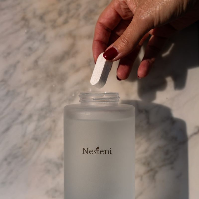 Hand lägger i tvåltablett i frostat glas från Nesteni