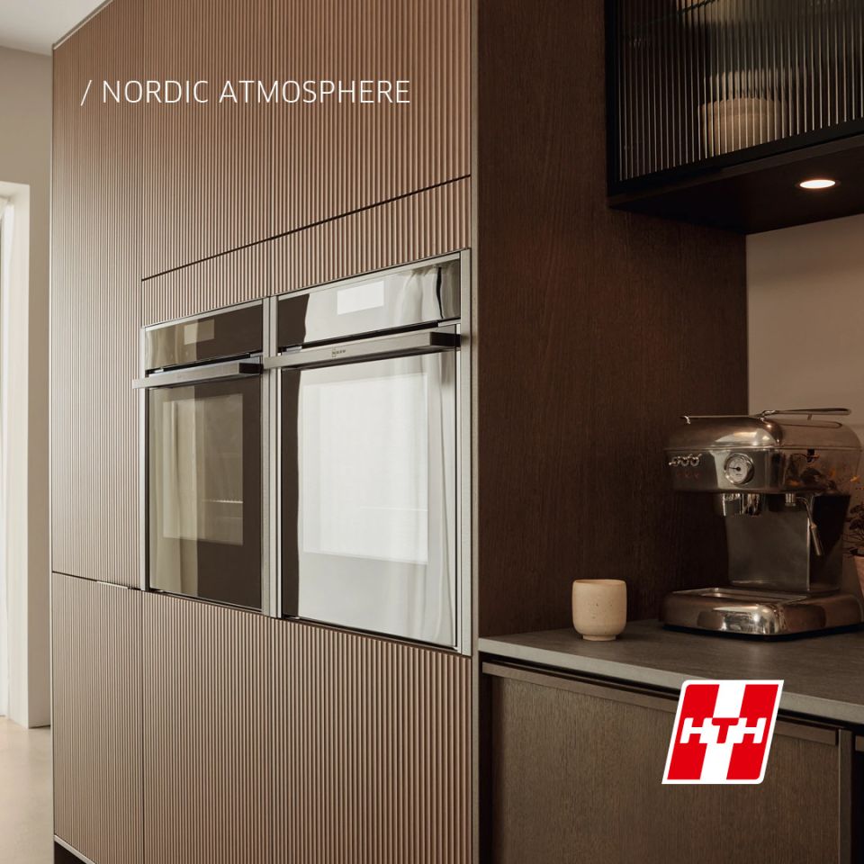  En detaljbild från ett HTH-kök i modellen Nordic Atmosphere som visar inbyggda ugnar i en ribbad träfront, vilket skapar en varm och exklusiv känsla i köksmiljön.