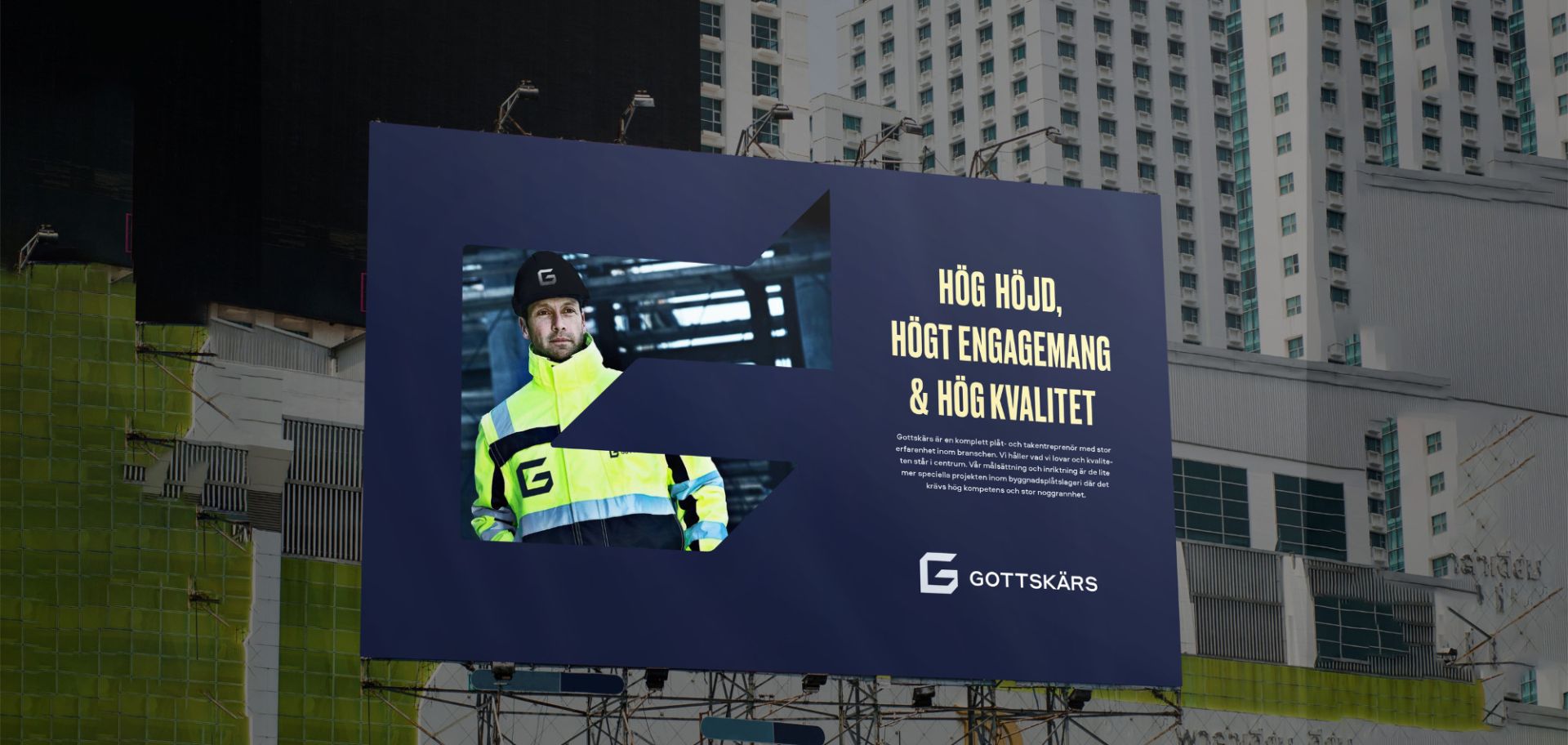 En stor utomhusreklam för Gottskärs i mörkblått med rubriken ”Hög höjd, högt engagemang & hög kvalitet”. Annonsen visar en professionell hantverkare i profilkläder genom en grafisk utskärning av företagets logotyp, monterad framför en stor byggnad.