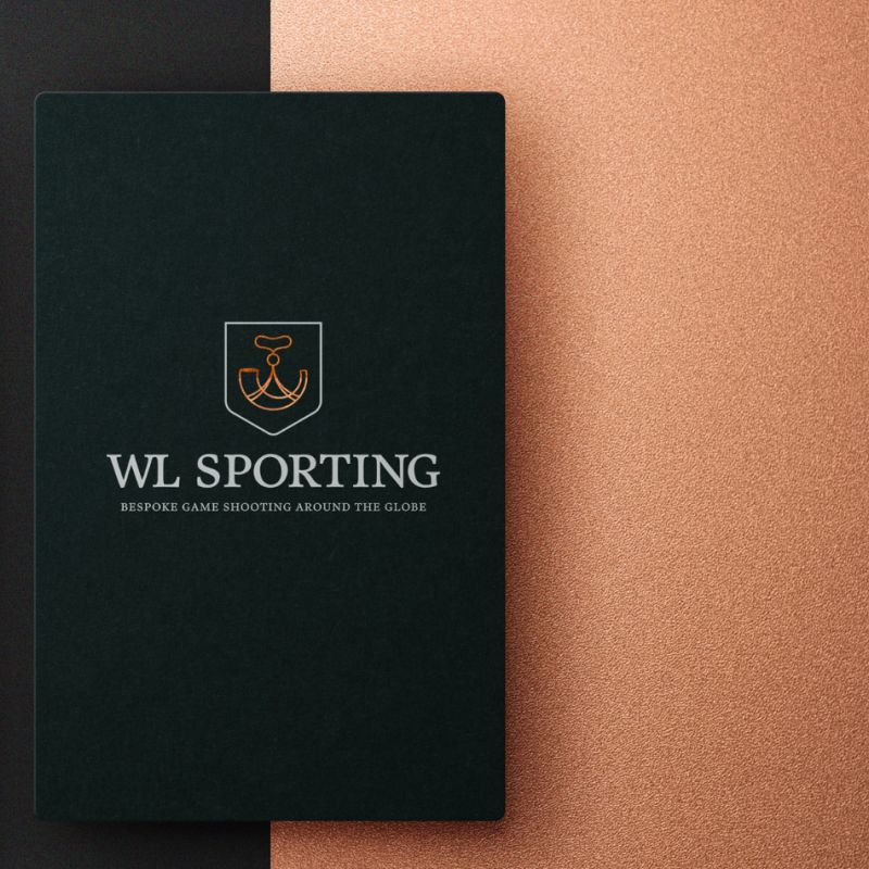  En närbild på WL Sportings logotyp tryckt i silver och guld på en mörk, texturerad yta, vilket framhäver företagets fokus på elegans och högklassig jakt.