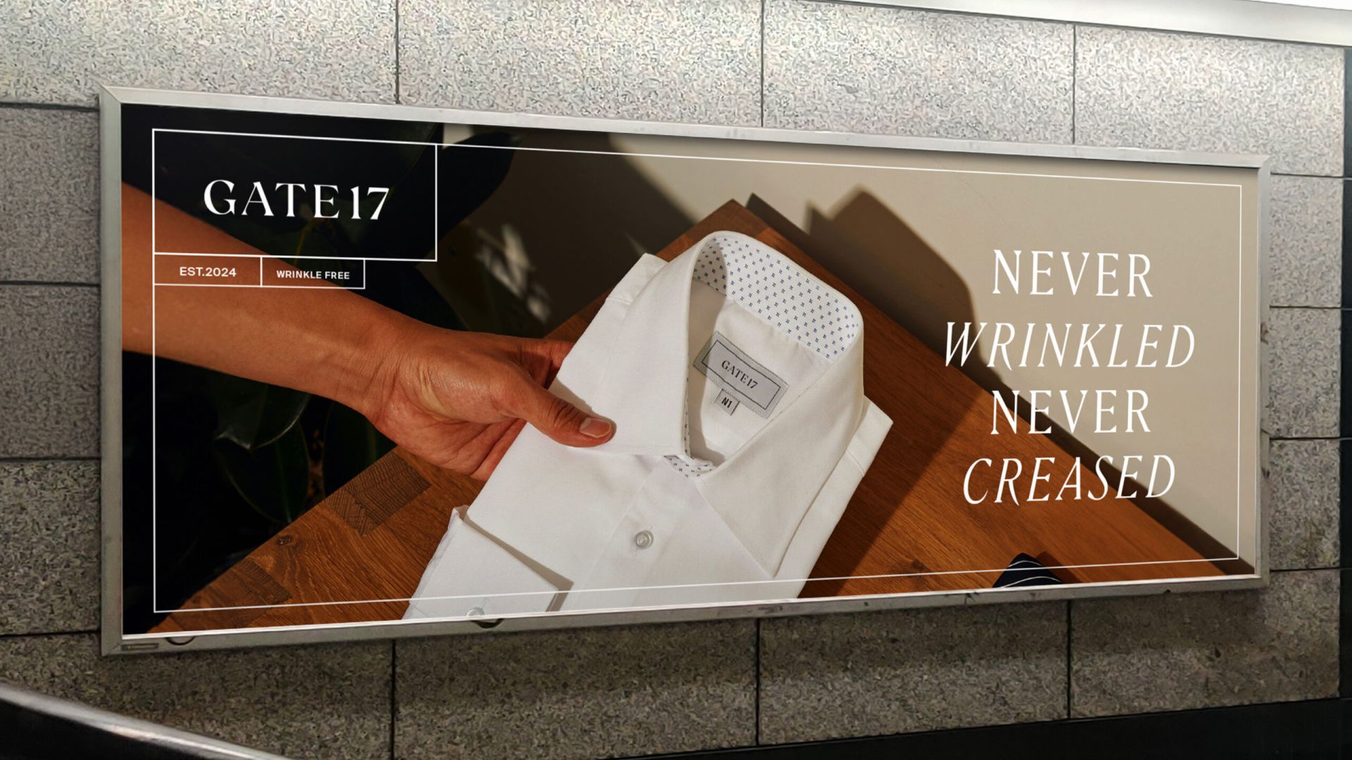 Reklamskylt för Gate 17 föreställande en vit skjorta med texten ”Never wrinkled, never creased”, i en klassisk och reseinspirerad design.