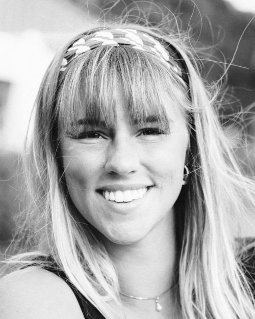 Porträtt av Sara Blixt, content creator, med långt hår och lugg, blickandes in i kameran med ett stort leende.