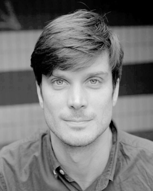 Porträtt av Simon Vahlne, regissör, med kort mörkt hår och en skjorta, blickandes in i kameran