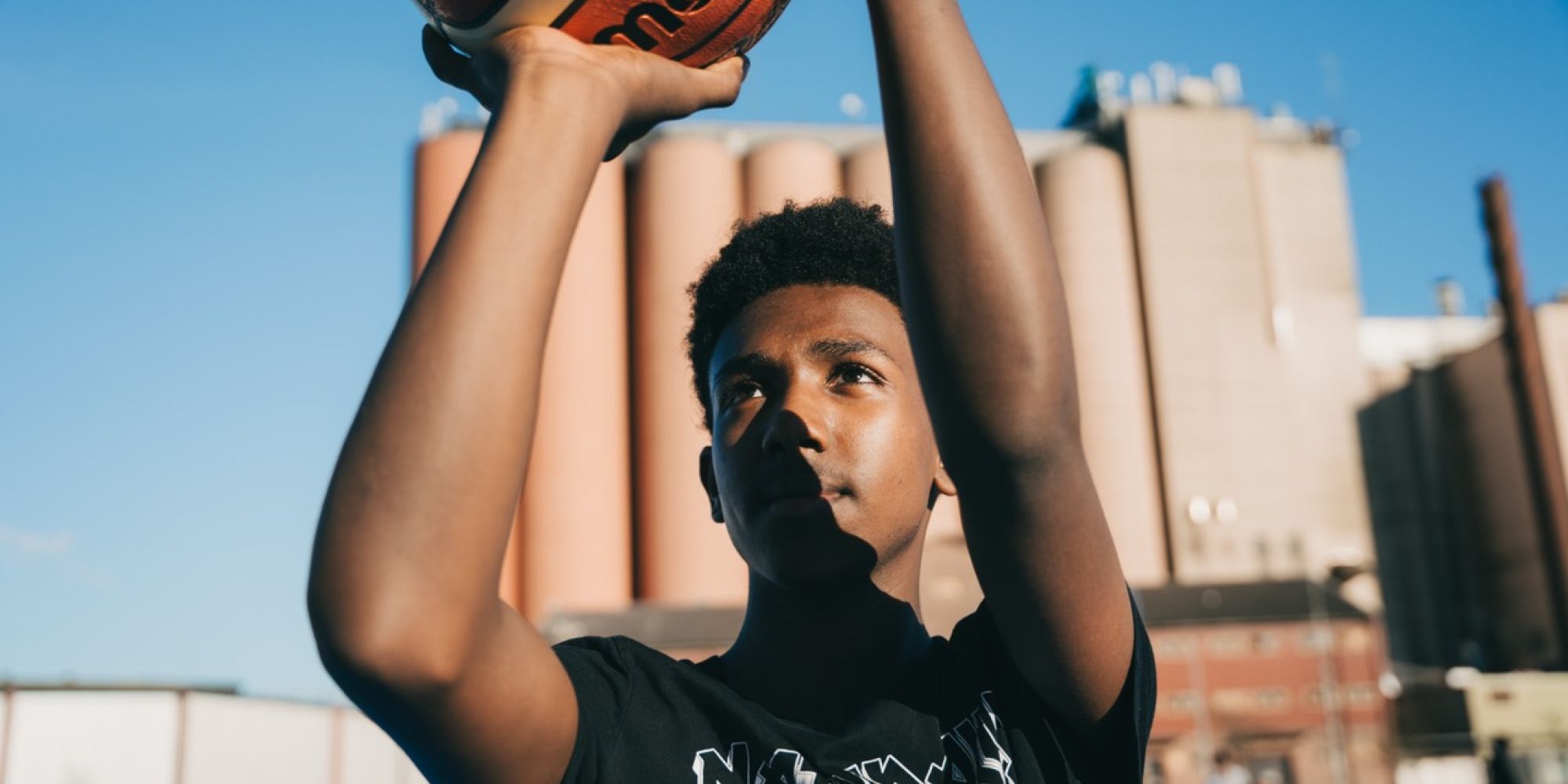 En fokuserad ung kille förbereder ett skott på basketplanen vid Västra Gärdet, ett lokalt projekt som finansierats genom Falkenbergs Sparbanks Framtidsbank.